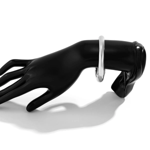 Dettaglio di un bracciale a goccia in argento lucido su un modello con finitura a specchio