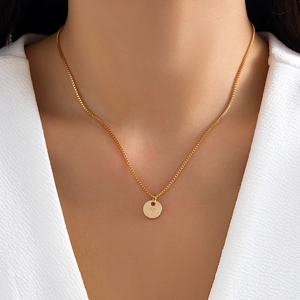 Minimalist gold necklace featuring a round pendant with letter Y engraving on a box chain