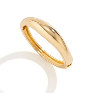 Dettaglio macro del bracciale rigido dorato lucido con finitura a specchio brillante