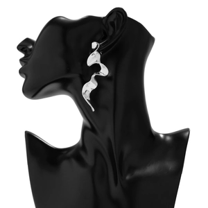 Primer plano de pendientes de metal líquido ondulado plateado en modelo negro