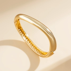 Detailed macro view of the gold mirrored bracelet with its hinge closure and textured inner