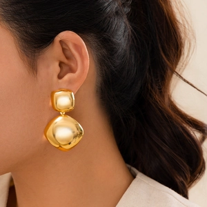 Close-up of geometric gold geometric earrings featuring double square drop design