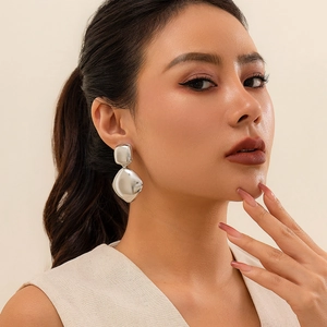 Macro shot of silver geometric drop earrings with polished finish on female model