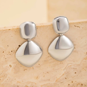Close-up of silver geometric dangle earrings with mirror finish on stone display
