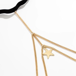 Detail of golden multilayer tassel leg chain with star pendant on a black elastic band