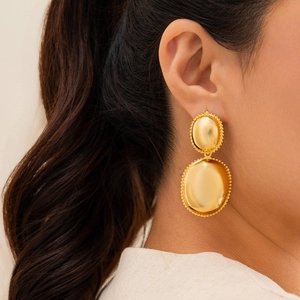 Close-up of double oval gold earrings with vintage beaded edges on model
