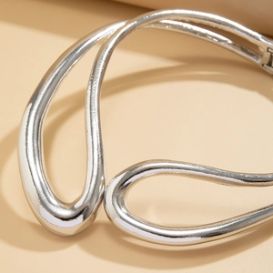 Gros plan d'un ras de cou argenté au design fluide avec surface métallique polie miroir