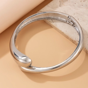 Dettaglio macro del bracciale rigido a goccia d'argento con finitura a specchio