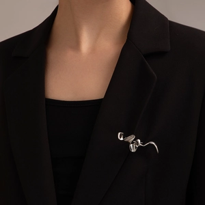 Primer plano del broche plateado de onda fluida sobre una elegante chaqueta negra