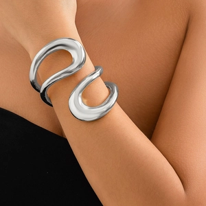 Gros plan d'un bracelet manchette argenté poli au design de métal liquide sur un modèle