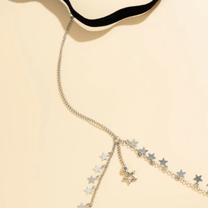 Close-up of silver metal leg chain with star pendants and black elastic band detail