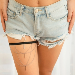 Close-up of multi-layer silver leg chain with geometric star pendants on denim shorts