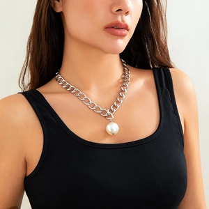 Macro detail of a chunky silver chain necklace featuring a large round pearl pendant