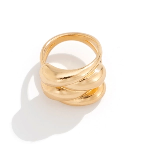 Macro view of wide irregular gold V-shaped bracelet with tiered metallic reflective surface