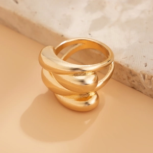 Gros plan d'une bague ondulée dorée multicouche avec finition polie sur support pierre