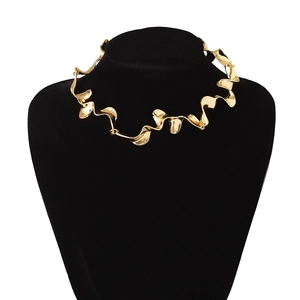 Primer plano de un collar geométrico ondulado dorado en un busto de exhibición negro