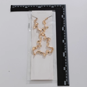Detalle de collar de metal dorado en espiral con escala de medida sobre tarjeta de joyería