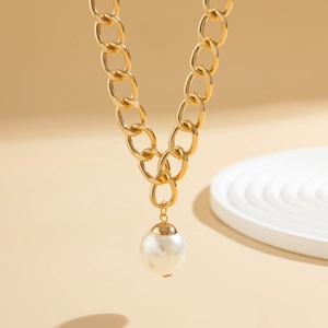 Detail of elegant gold chunky chain necklace featuring a large round pearl pendant