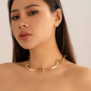 Detalle de un collar ondulado de metal líquido dorado usado por una modelo elegante
