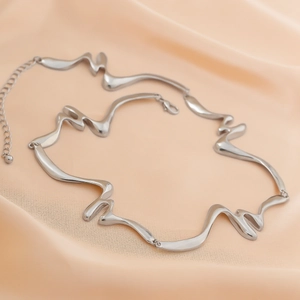 Detalle del collar de eslabones de metal líquido plateado sobre seda rosa suave