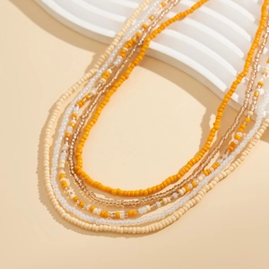 Détail d'une chaîne de taille multicouche en perles orange et beige style de plage