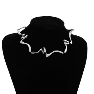 Detalle del collar de metal líquido con diseño geométrico trenzado en soporte de exhibición