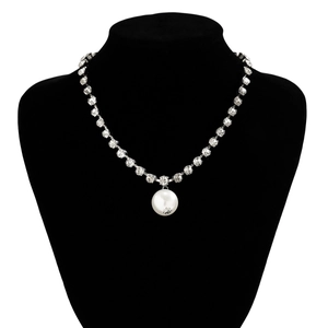 Macro detail of elegant faux pearl pendant on a sparkling crystal necklace for women