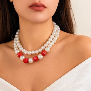 Detailansicht der zweilagigen Perlenkette mit roten LOVE-Perlen an einem Model