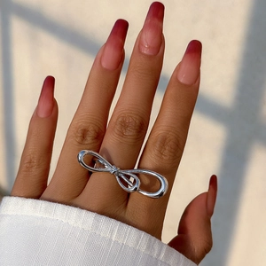 Close-up of a polished silver bow-shaped double finger ring worn on a hand