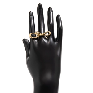 Polished gold metal bow ring displayed on a black hand model against white background