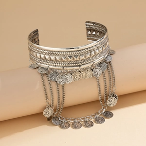 Detail of silver western cuff with metal tassels and coin charms in bohemian style