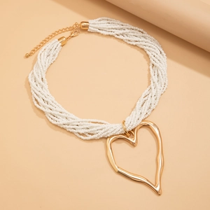Détail d'un collier de perles blanches multicouches avec un grand pendentif cœur doré