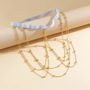 Detailed view of layered gold bead leg chains with white elastic thigh band on display