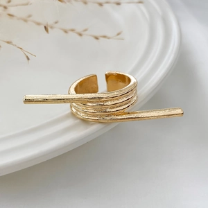 Close-up of golden multi-layer ring with hammered metal texture on white ceramic tray