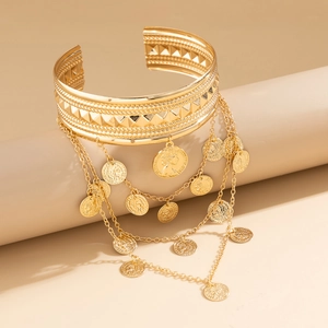 Detail of bohemian gold arm cuff with layered chain tassels and vintage coin pendants