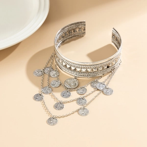 Detail of vintage silver arm cuff with geometric embossing and metal tassel coin charms