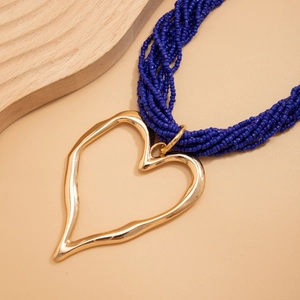 Détail du pendentif cœur doré et du collier de perles bleu marine à plusieurs rangs