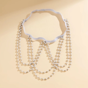 Detail of layered leg chain with white faux pearls and silver metal tassels on elastic band