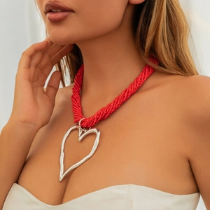 Gros plan du collier multicouche de perles rouges avec un grand pendentif cœur argenté