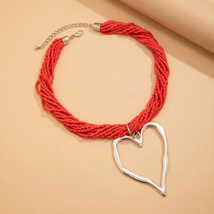 Détail macro de perles rouges multirangs avec pendentif cœur argenté imposant