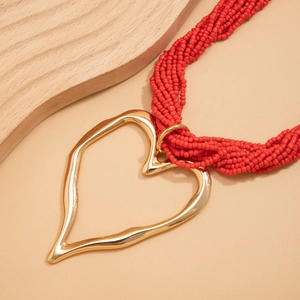 Vue détaillée du collier de perles rouges multi-rangs avec pendentif cœur doré irrégulier