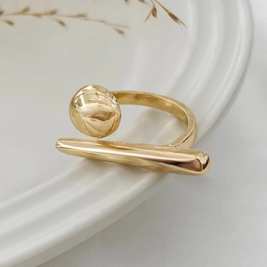 Macro detail of a minimalist gold geometric ring featuring polished sphere and cylinder accents