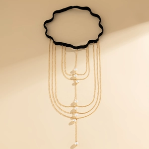 Close-up of bohemian layered gold leg chain with white pearls on a black elastic band