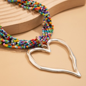 Gros plan sur un collier de perles colorées multicouches avec pendentif cœur texturé