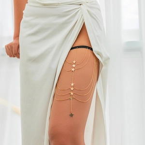 Detail of layered gold star leg chain with black elastic band on female model