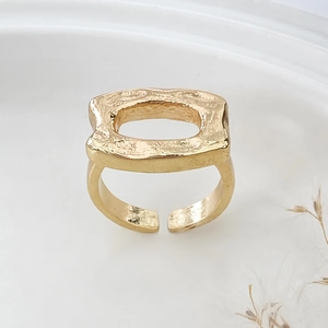 Detail view of adjustable gold ring featuring hollow rectangular top and hammered metal texture