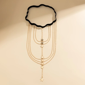 Detailed view of layered gold leg chain with star charms and black elastic band