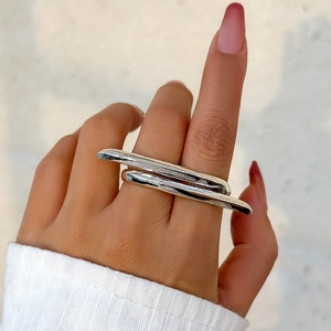 Close-up of polished silver metal double-finger ring with minimalist abstract design