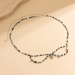 Detalle de cadena para cintura con cuentas blancas y negras y piedras naturales verdes