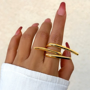 Macro shot of minimalist gold layered ring bands on finger with modern artistic design
